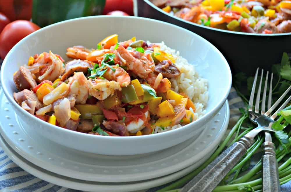 White bowl filled with cajun shrimp and sausage over rice.