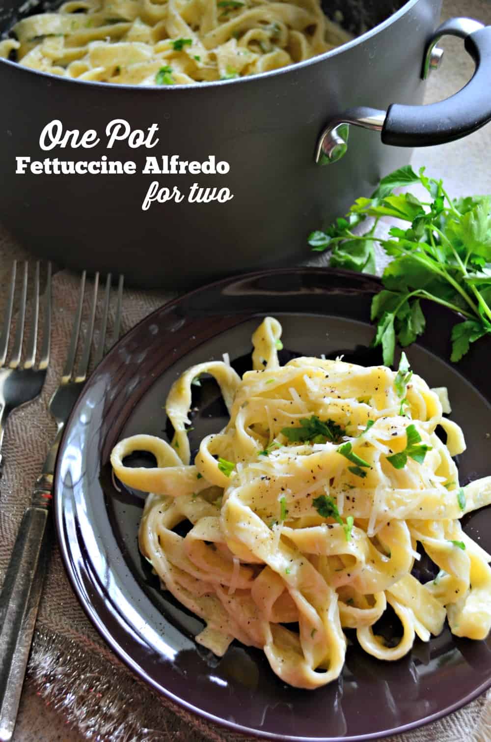 Photo of a pot Fettuccine Alfredo in the background with a plate of fettuccine noodles in the foreground.