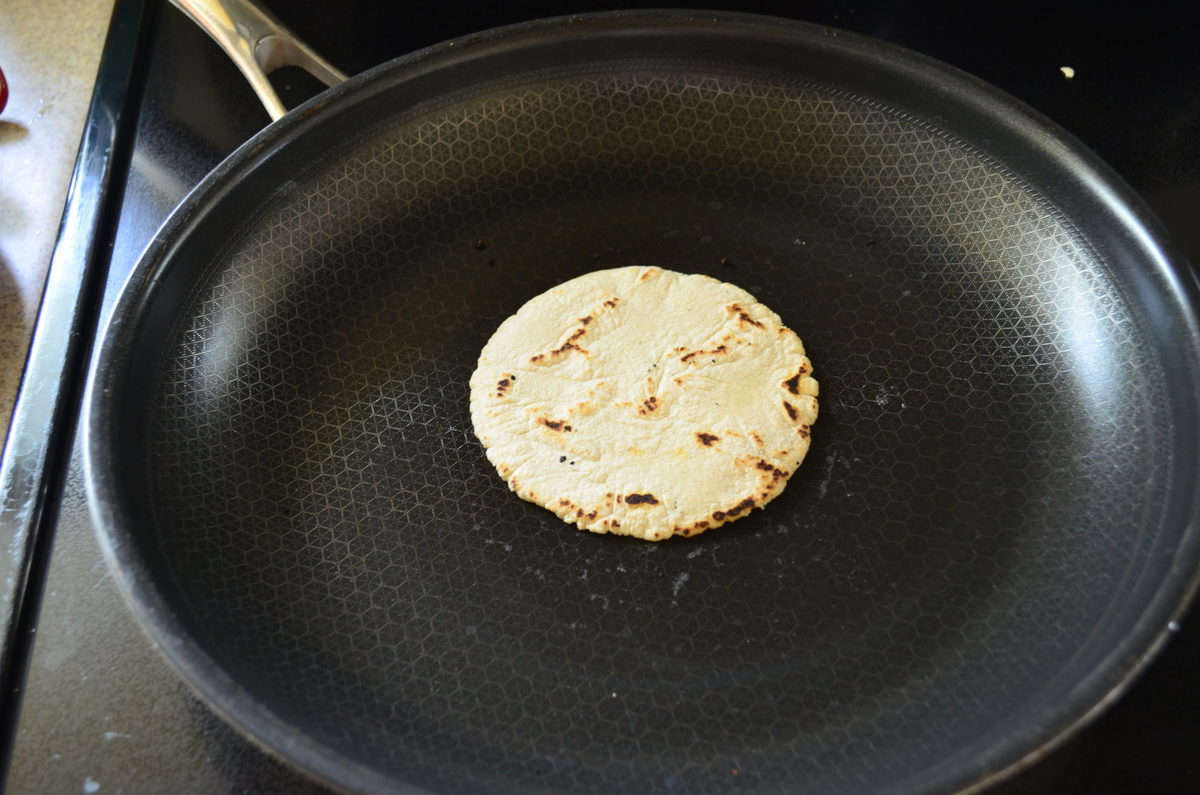 Round small tortilla on a frying pan browning. 