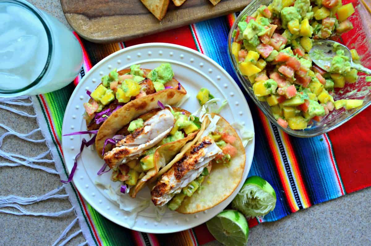 top view 4 plated Mahi Mahi Fish Tacos with Mango Avocado Salsa next to bowl of salsa.