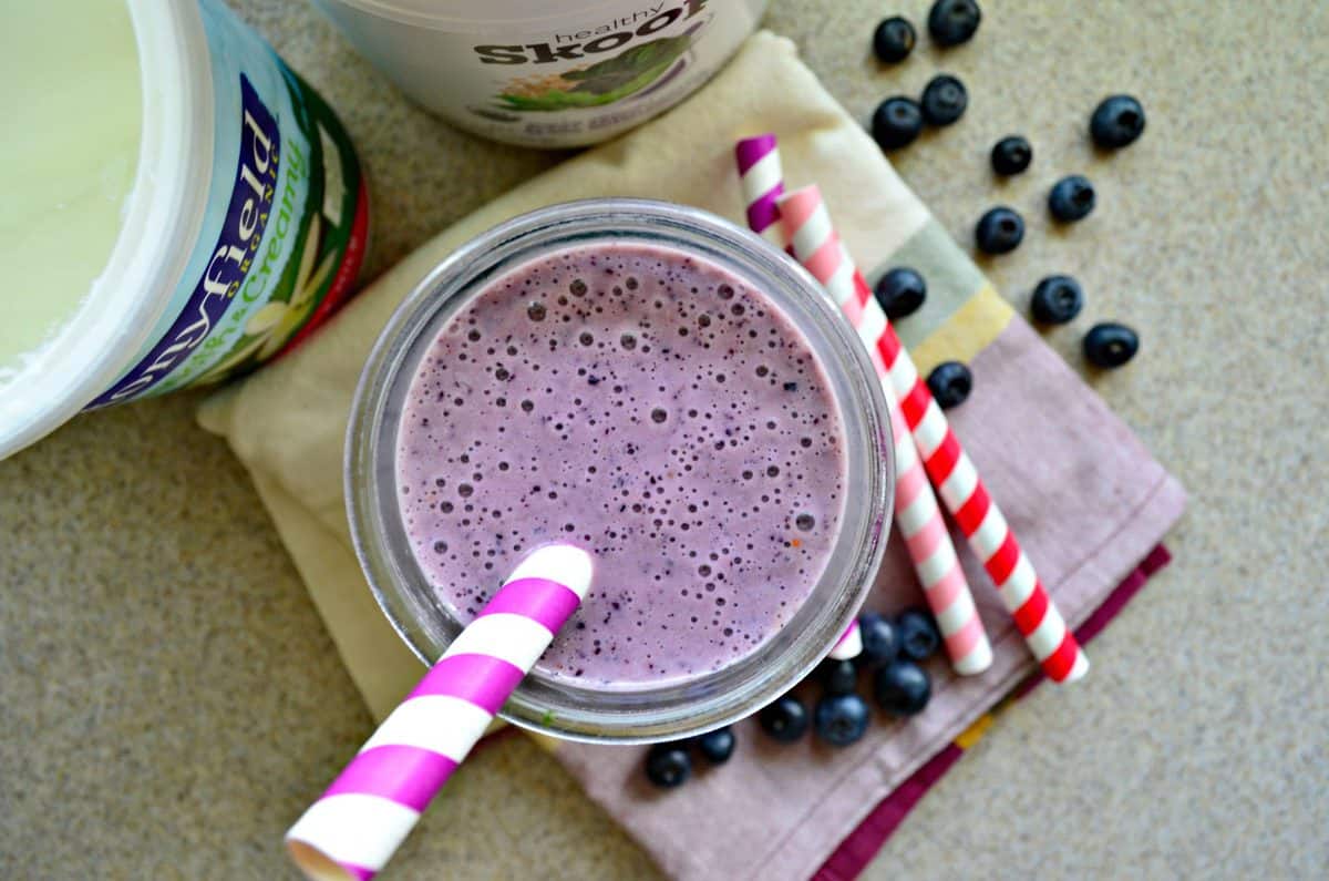 Top view of a purple smoothie with a purple and white striped straw. 