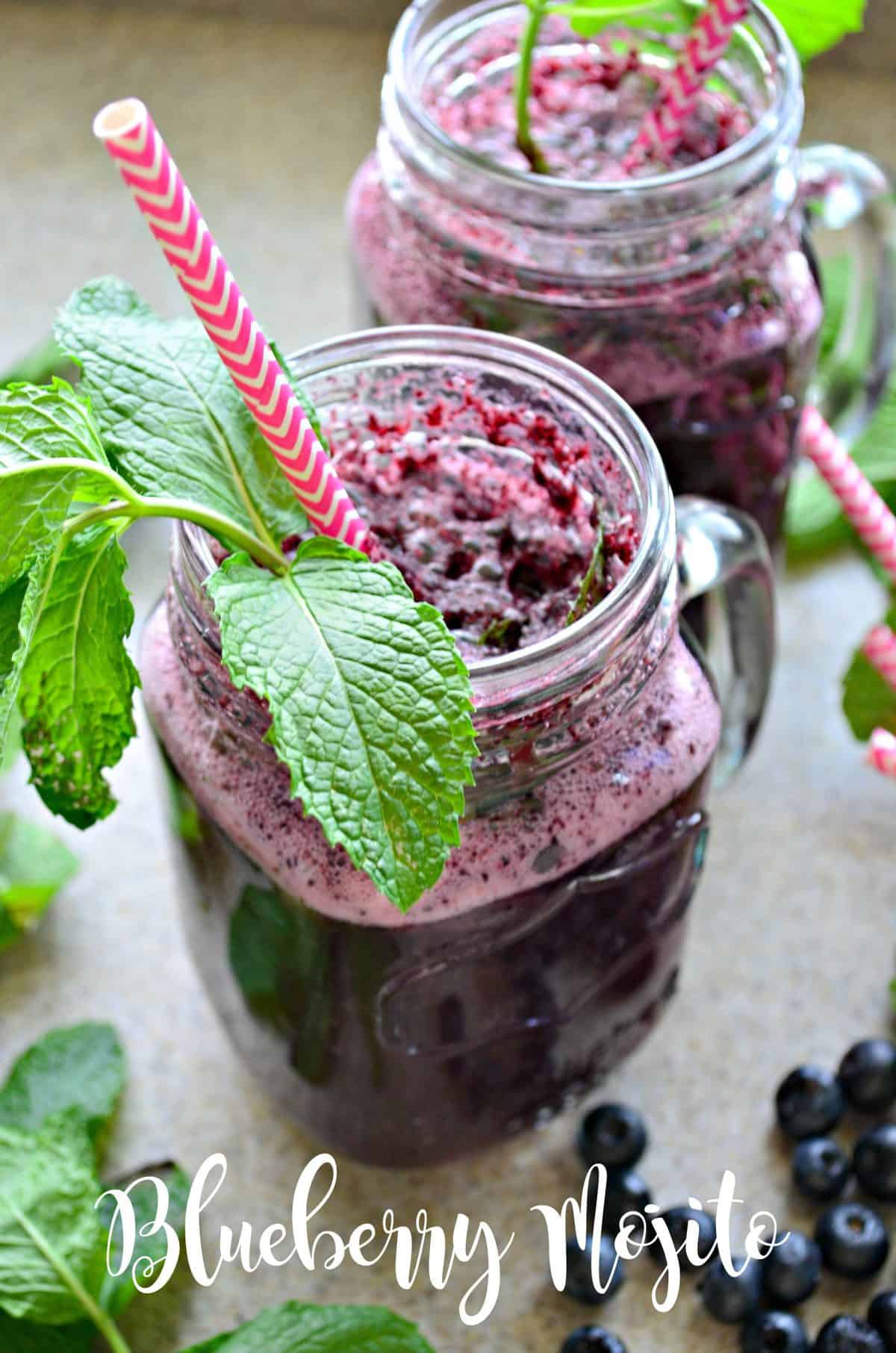 Top view of a sprig of mint with pink straw in a blueberry drink.