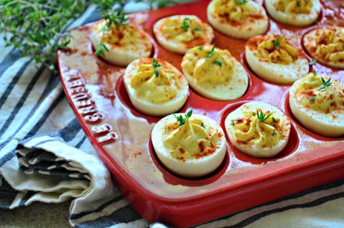 side view of deviled eggs topped with red seasoning in red egg dish.
