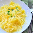 White bowl filled with spaghetti squash and chopped parsley.