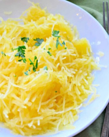 White bowl filled with spaghetti squash and chopped parsley.
