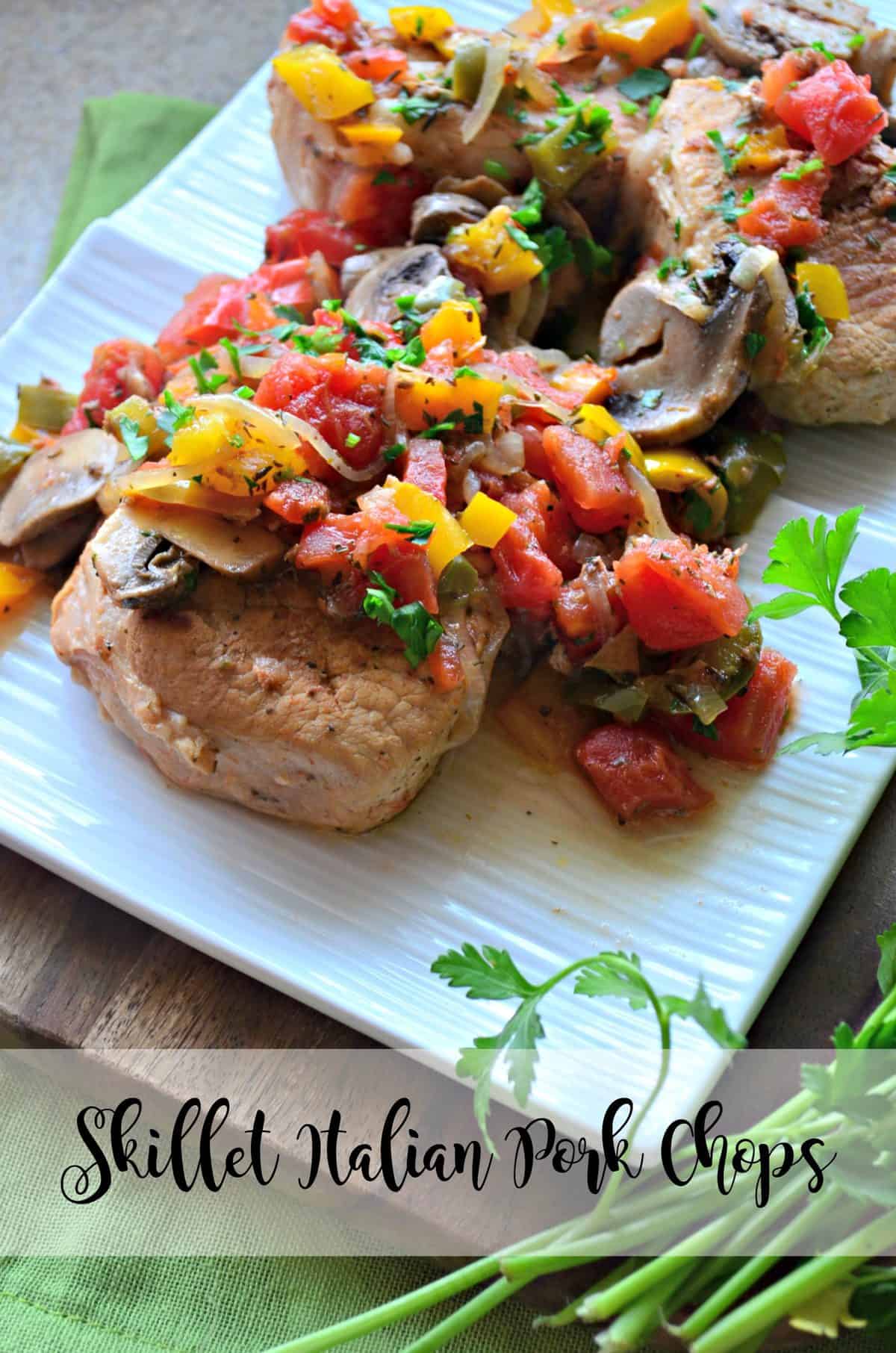 closeup top view of pork chops covered in herbs, tomatoes, mushrooms, and parsley plated with title text.