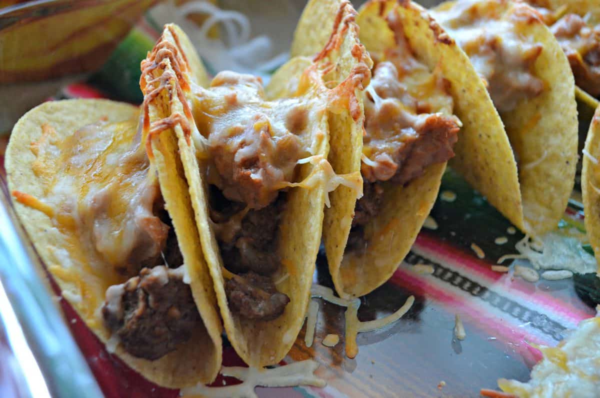 closeup Beef & Refried Bean Baked Tacos in glass casserole dish covered with melted cheese.