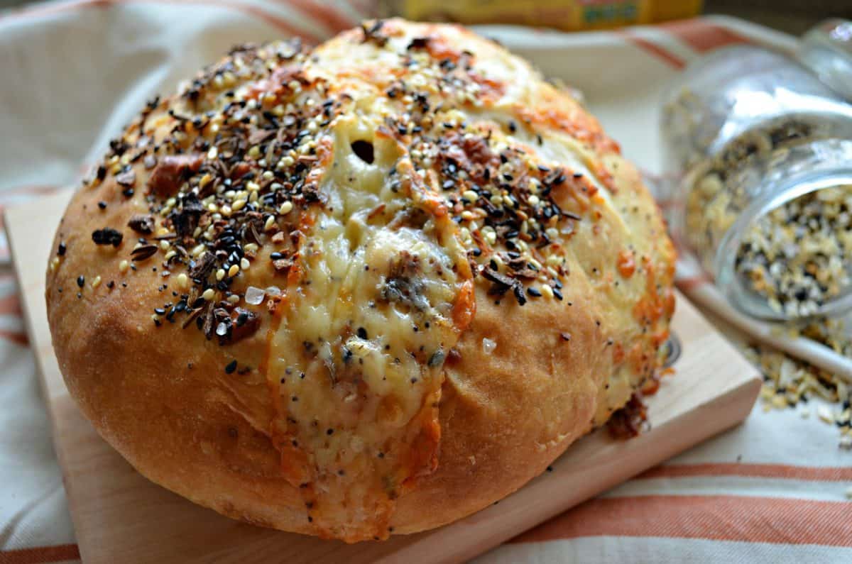 closeup of Cheesy No-Knead Crusty White Bread sprinkled with everything bagel seasoning on tablecloth.