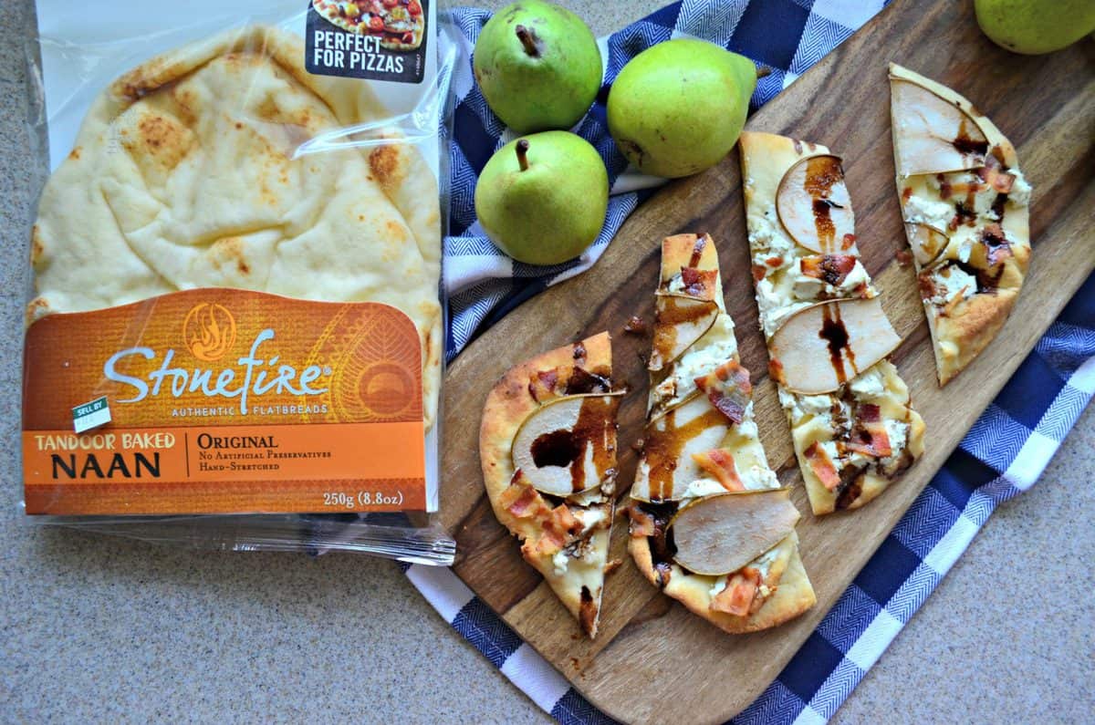 Goat Cheese, Bacon, and Pear slices on naan topped with brown sauce drizzled on board next to naan package.