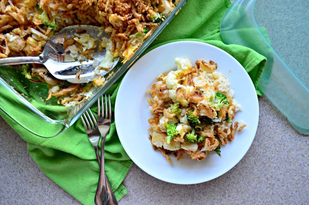 top view of Chicken Rice and Broccoli Casserole topped with crispy onions in casserole dish and plated next to silverware.