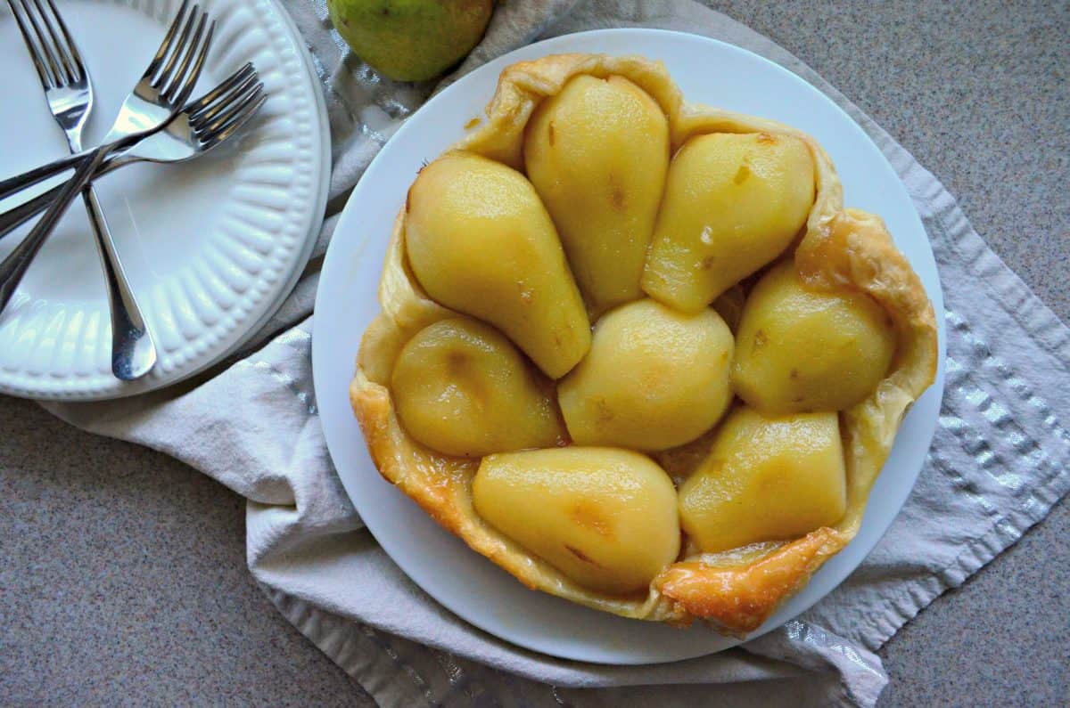  pastry-like crust filled with peeled golden pears on a white plate.