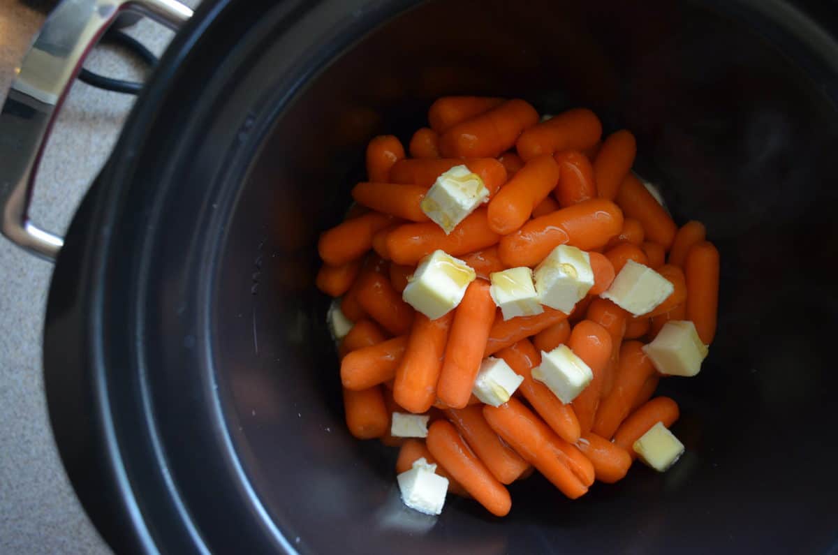 top view of carrots, chunks of butter, and honey in instant pot.