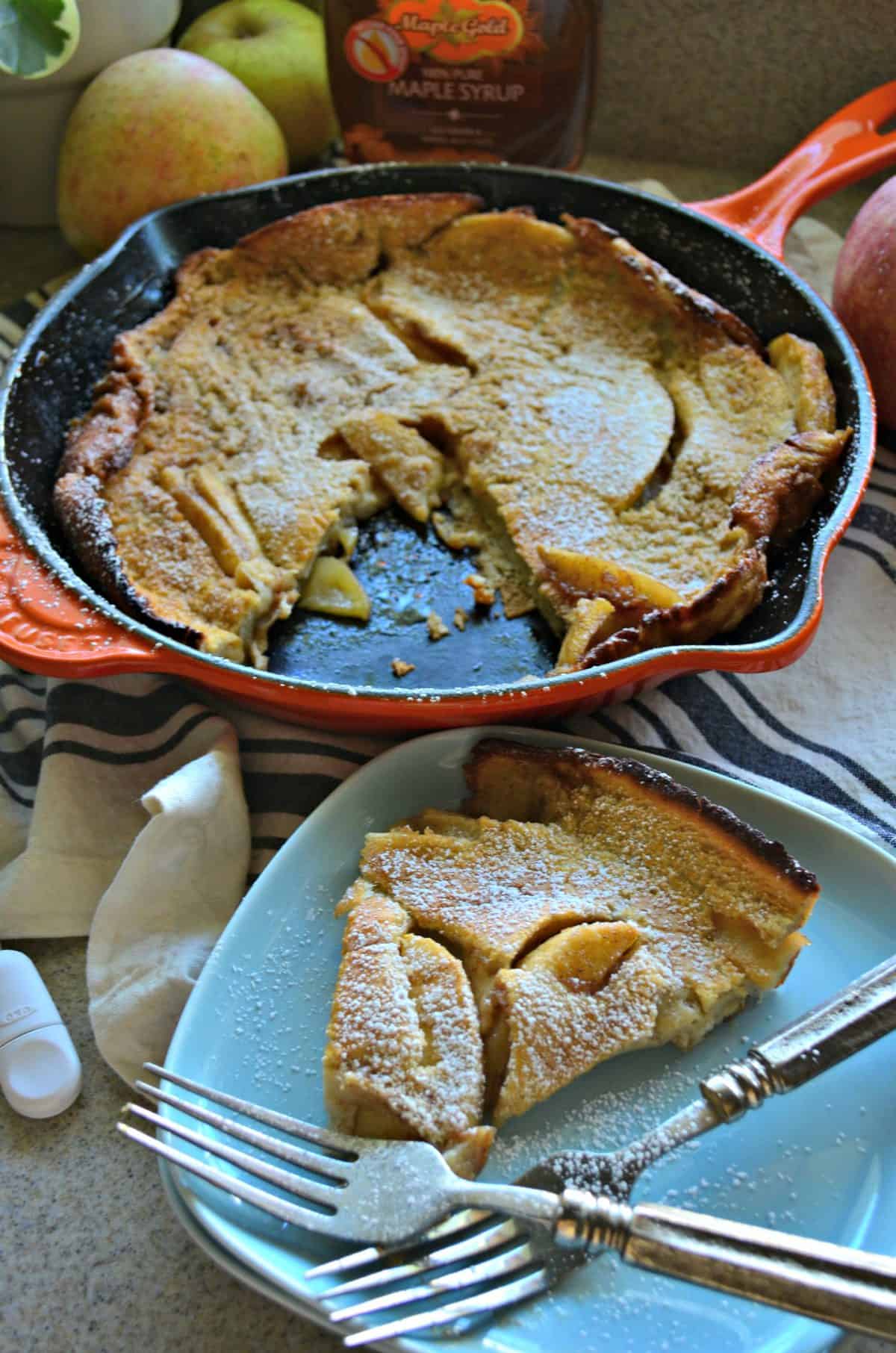 top view of pancake-like pastry with apple slices baked in, topped with powdered sugar next to plated slice.