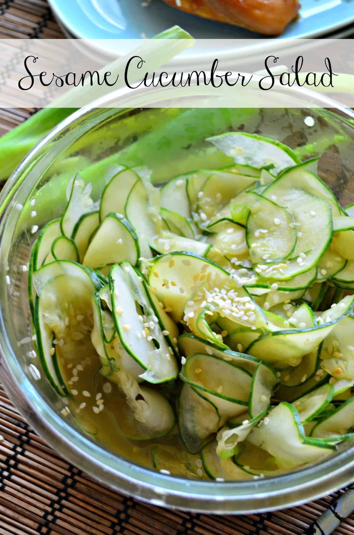 Close up of thinly sliced cucumbers with sesame seeds in a glass bowl with text on image.