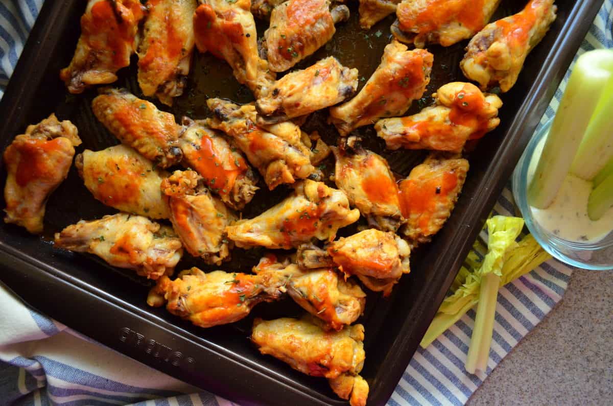 top view closeup of wings smothered in buffalo sauce and spices on sheet pan.
