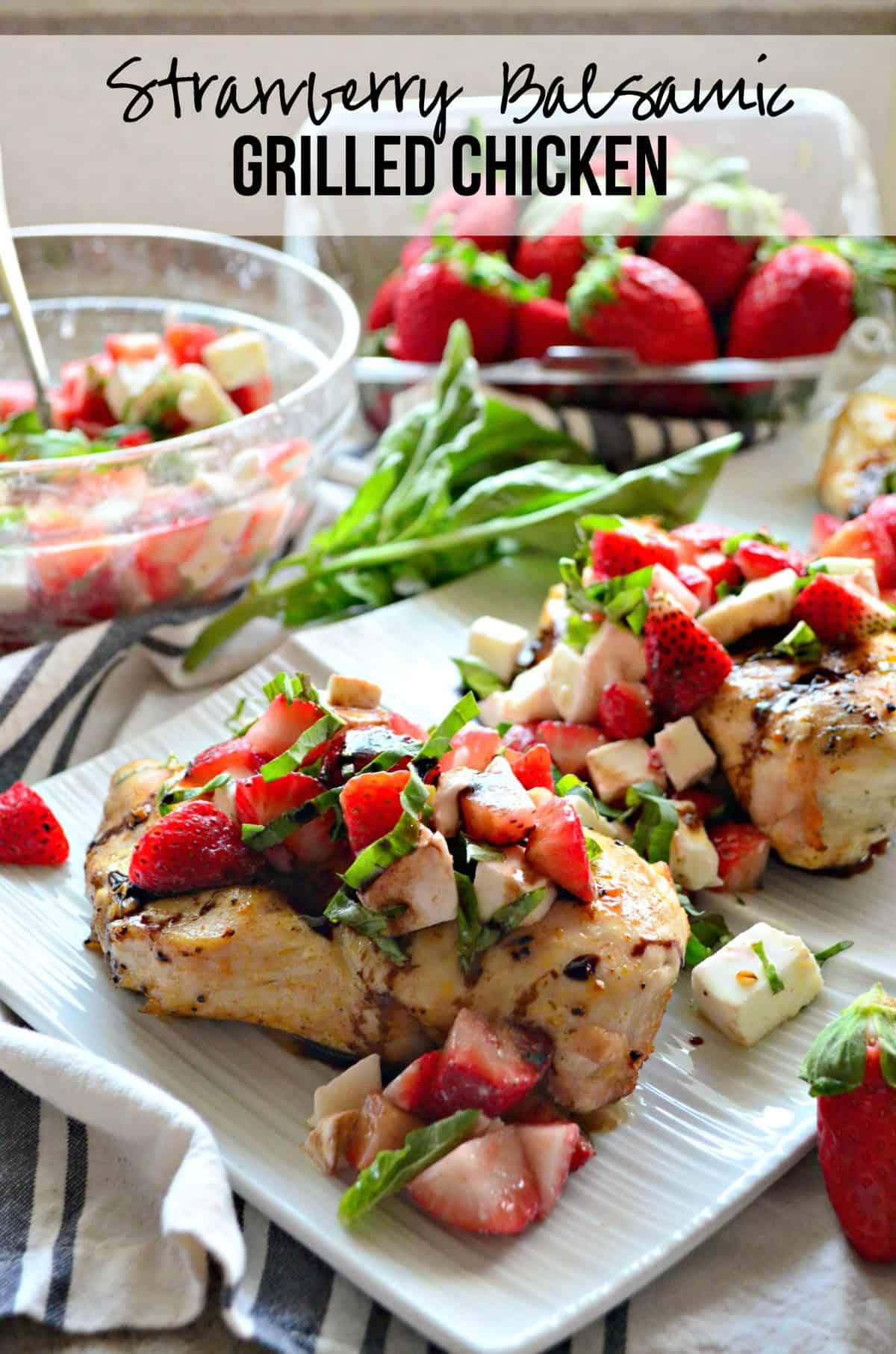 closeup grilled chicken topped with basil, strawberries, and balsamic sauce on white platter with text.