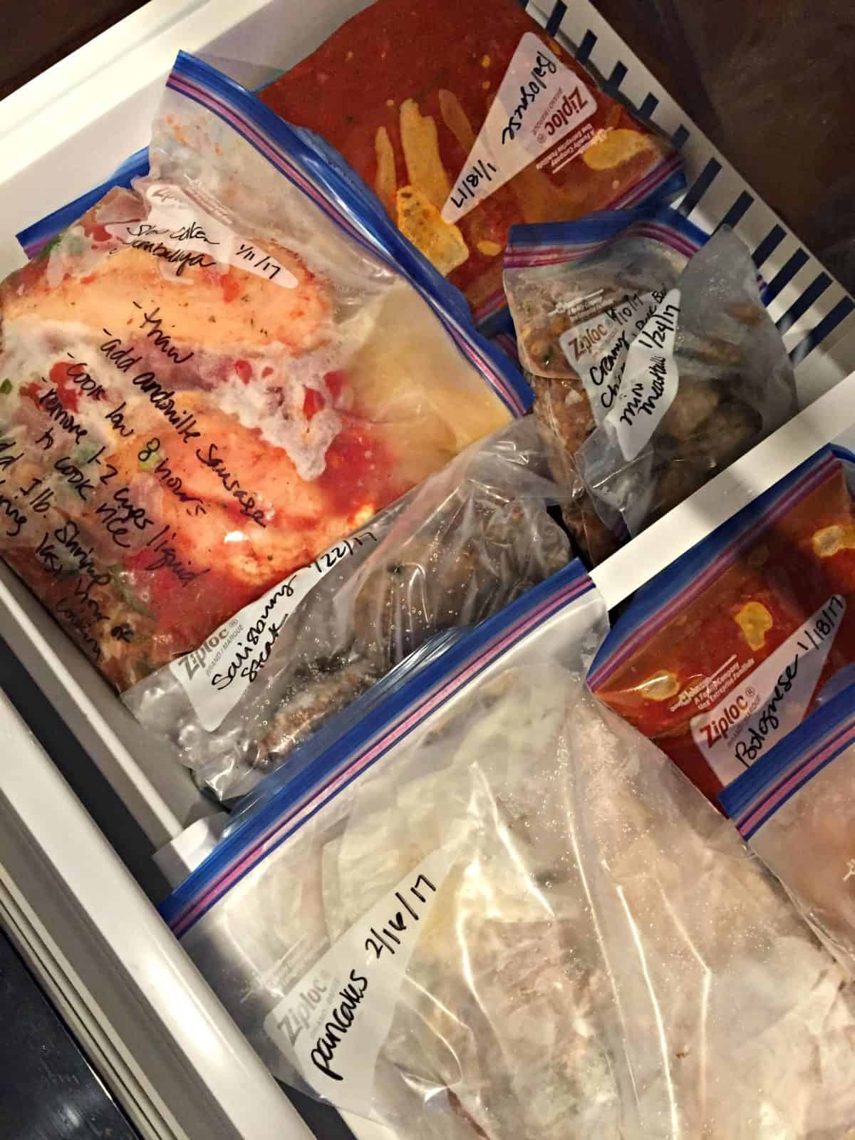 assorted frozen foods in zip lock bags in freezer drawer with title text for pinterest.