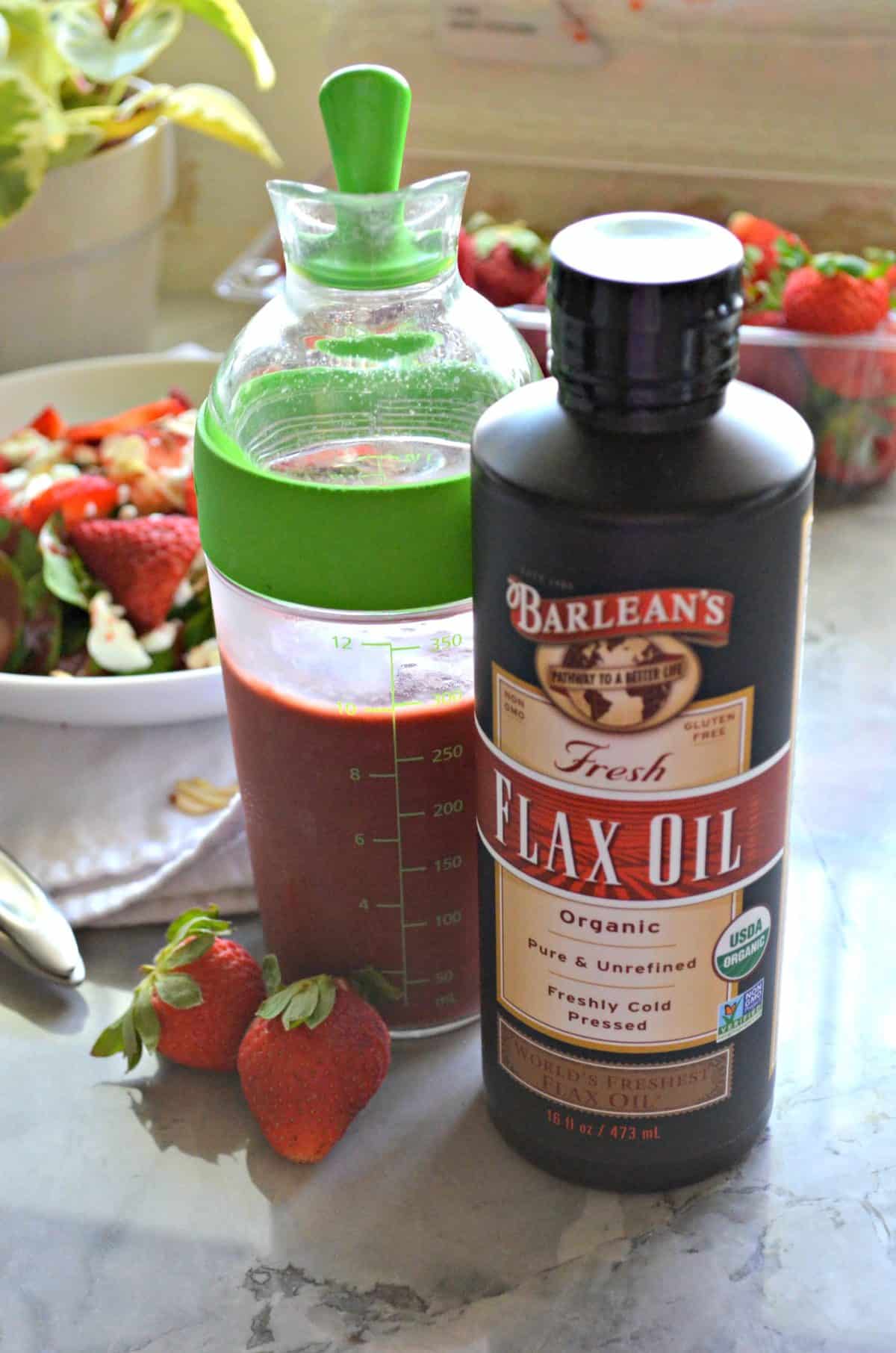 salad dressing container filled with pink seedy liquid next to barlean's fresh flax oil.