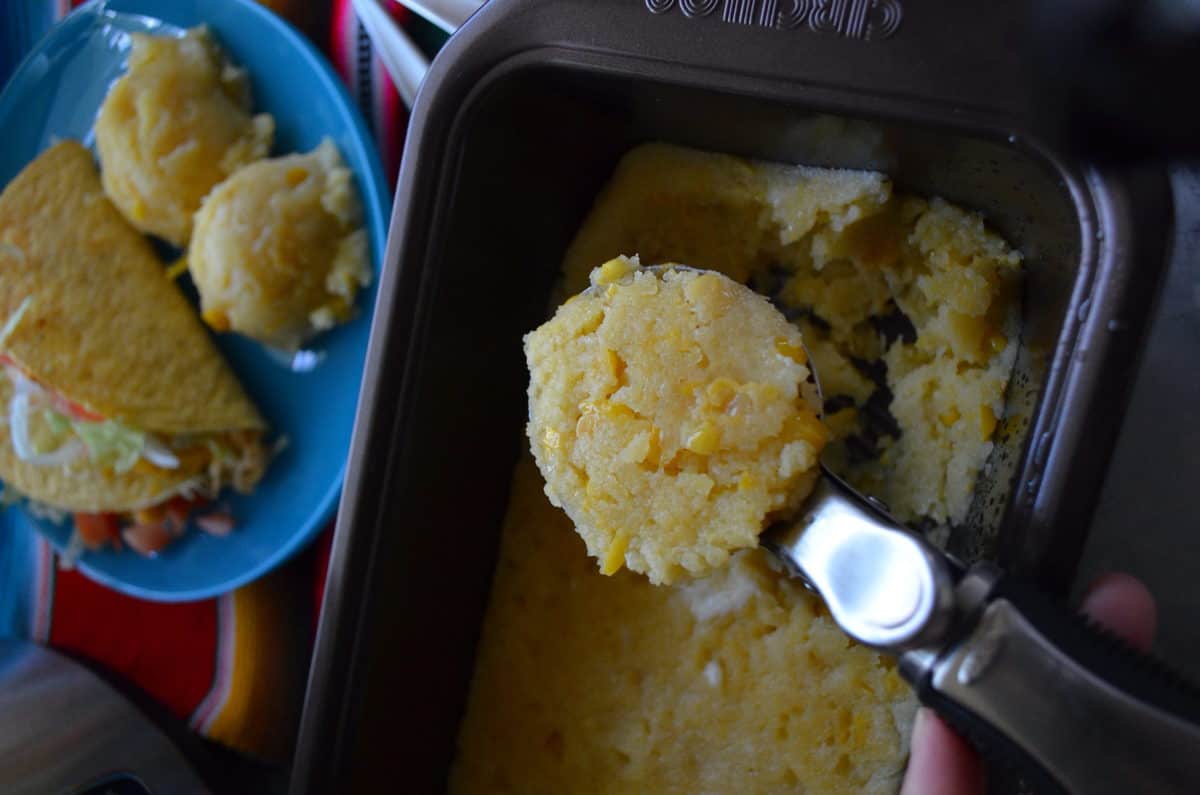 ice cream scooper scooping out corn cakes from bread pan.