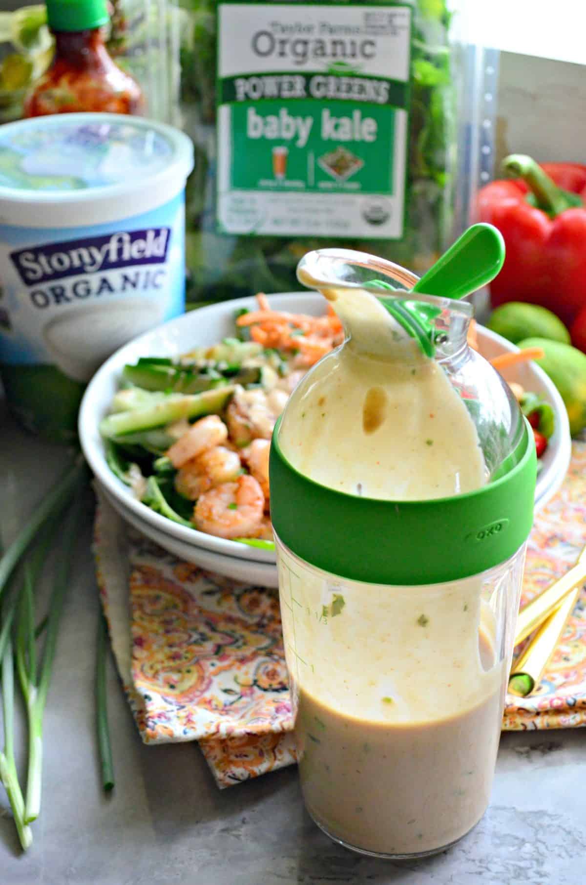 close up of container filled with homemade yogurt dressing in front of thai salad.