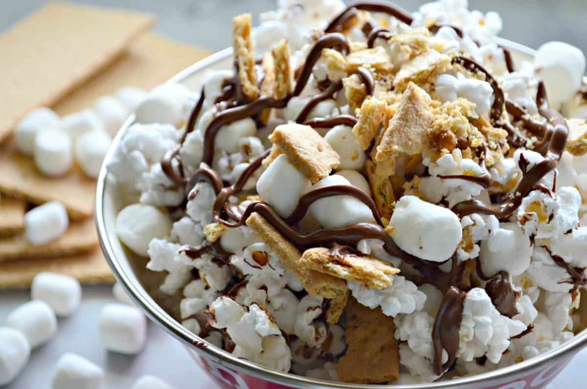 close up bowl of popcorn with graham crackers, chocolate drizzles, and mini marshmallows.