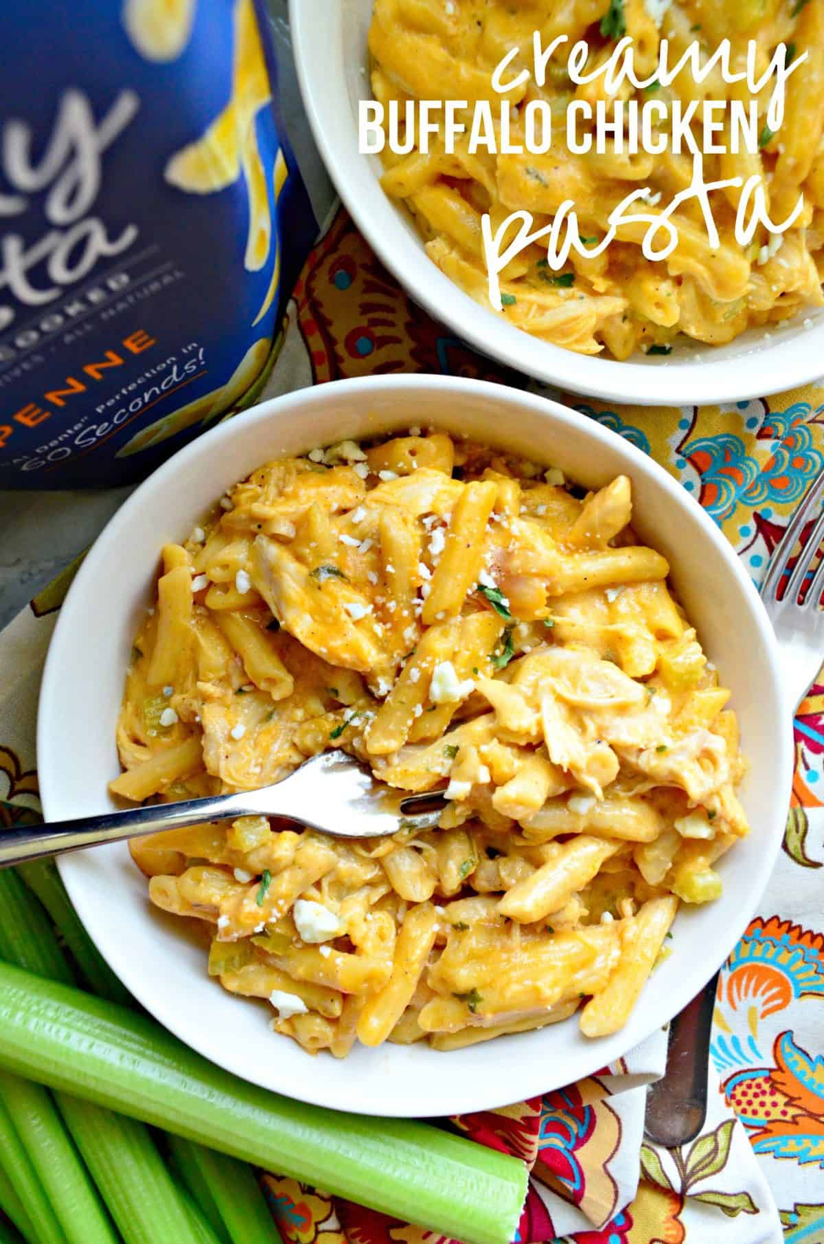 creamy light orange colored buffalo chicken penne pasta in white bowl with herbs, cheese, and title text.