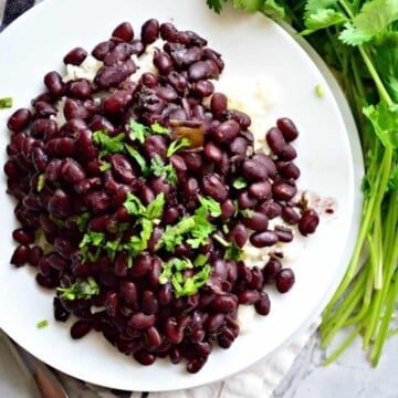 Top view of black bean sgarnished with cilantro on a white plate.