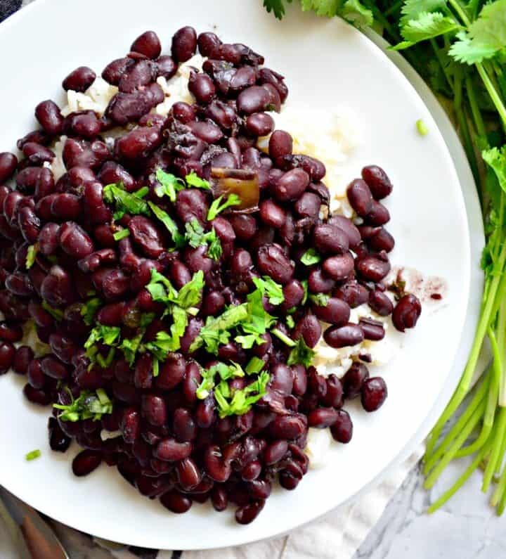 Top view of black bean sgarnished with cilantro on a white plate.