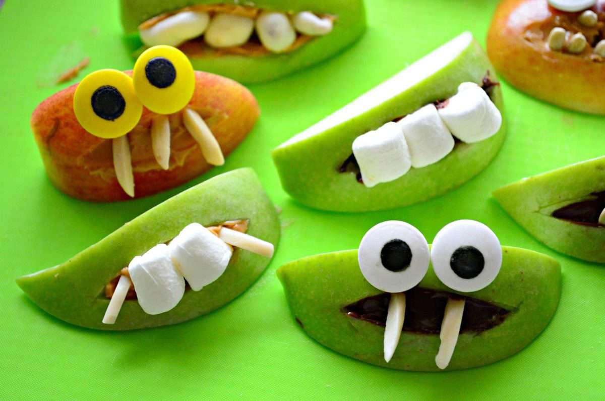 assorted apple slice monsters with marshmallows and nuts for teeth.