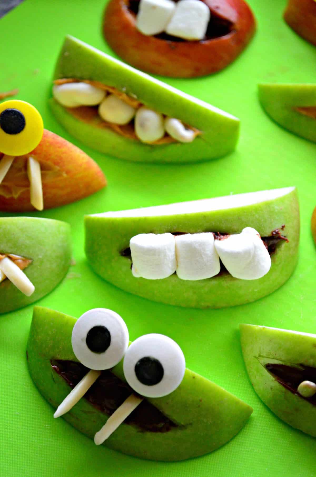 close up of assorted apple slice monsters with marshmallows and nuts for teeth.