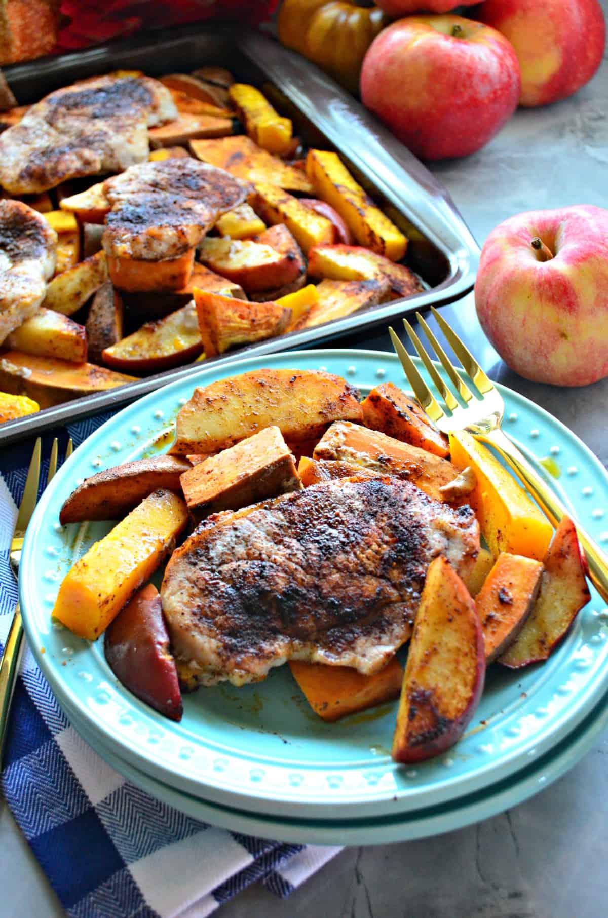 plated seasoned pork chops, sliced apples, and sliced butternut squash next to sheetpan of more.