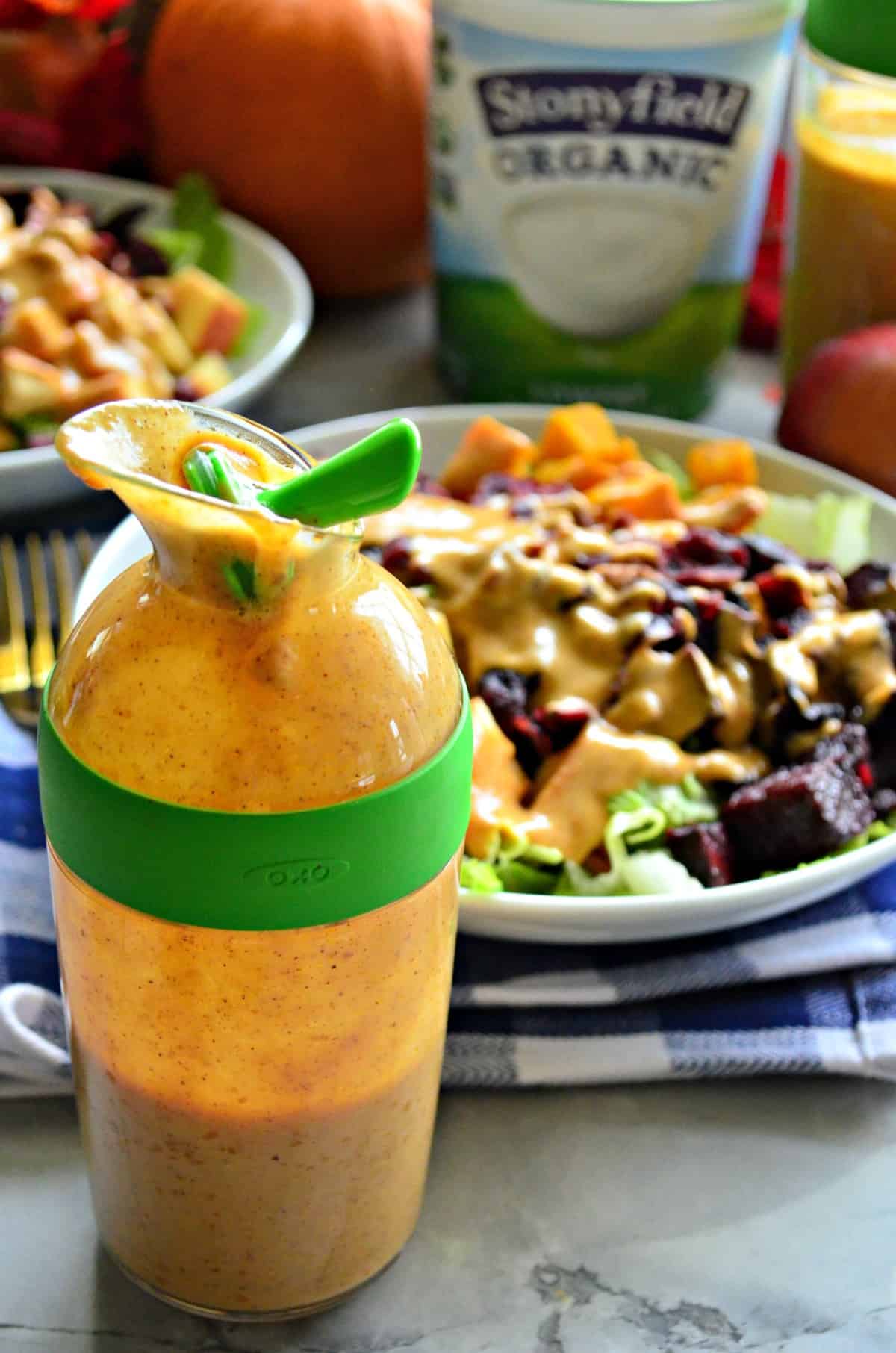 Close up of Pumpkin Yogurt Dressing in home dressing container in front of salad.