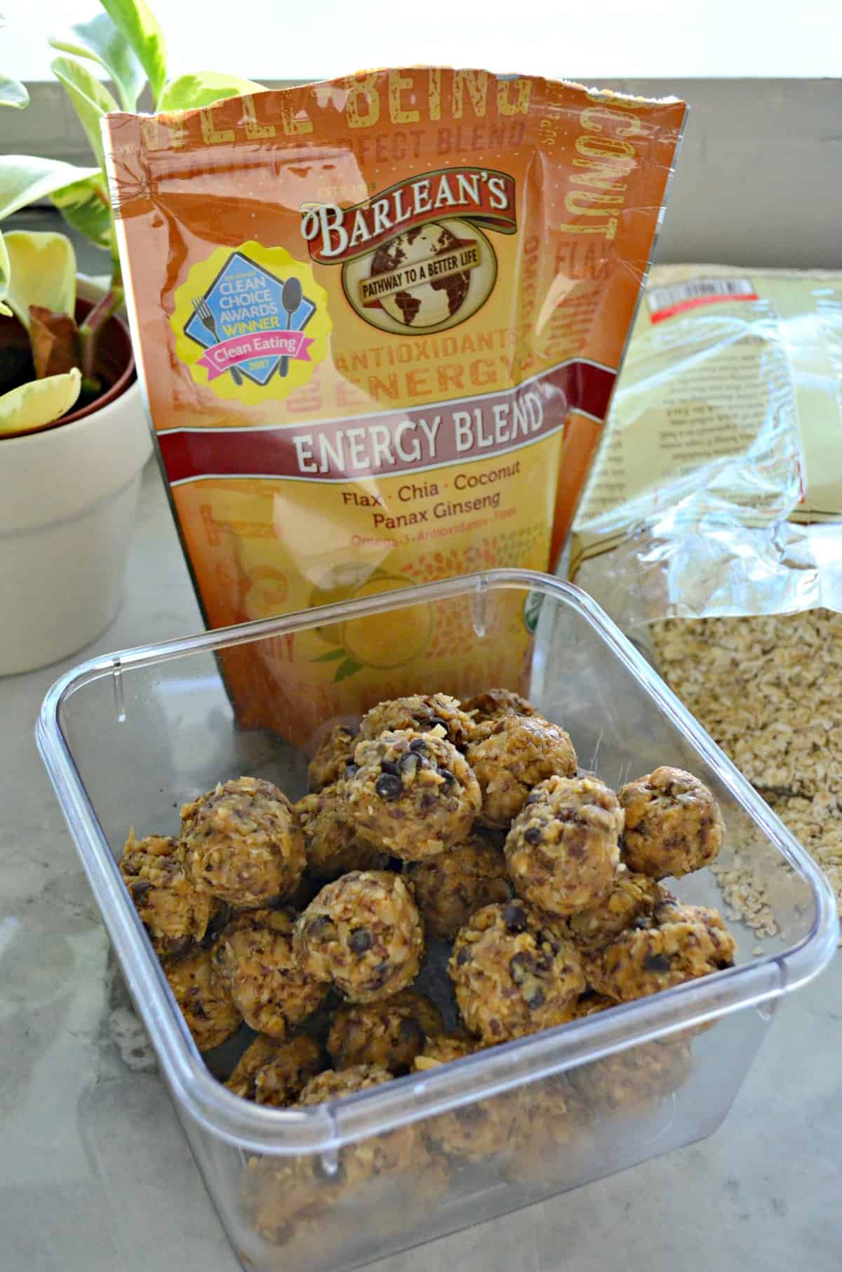 Peanut Butter Chocolate Chip Protein Balls in container on countertop in front of Barlean's Energy Blend.