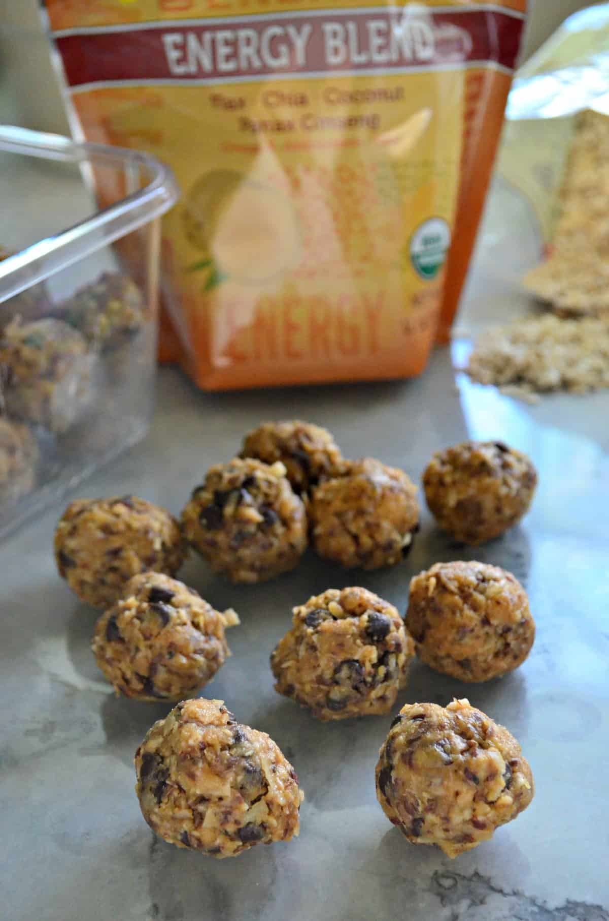 Peanut Butter Chocolate Chip Protein Balls on countertop in front of ingredients and tupperware with title text.