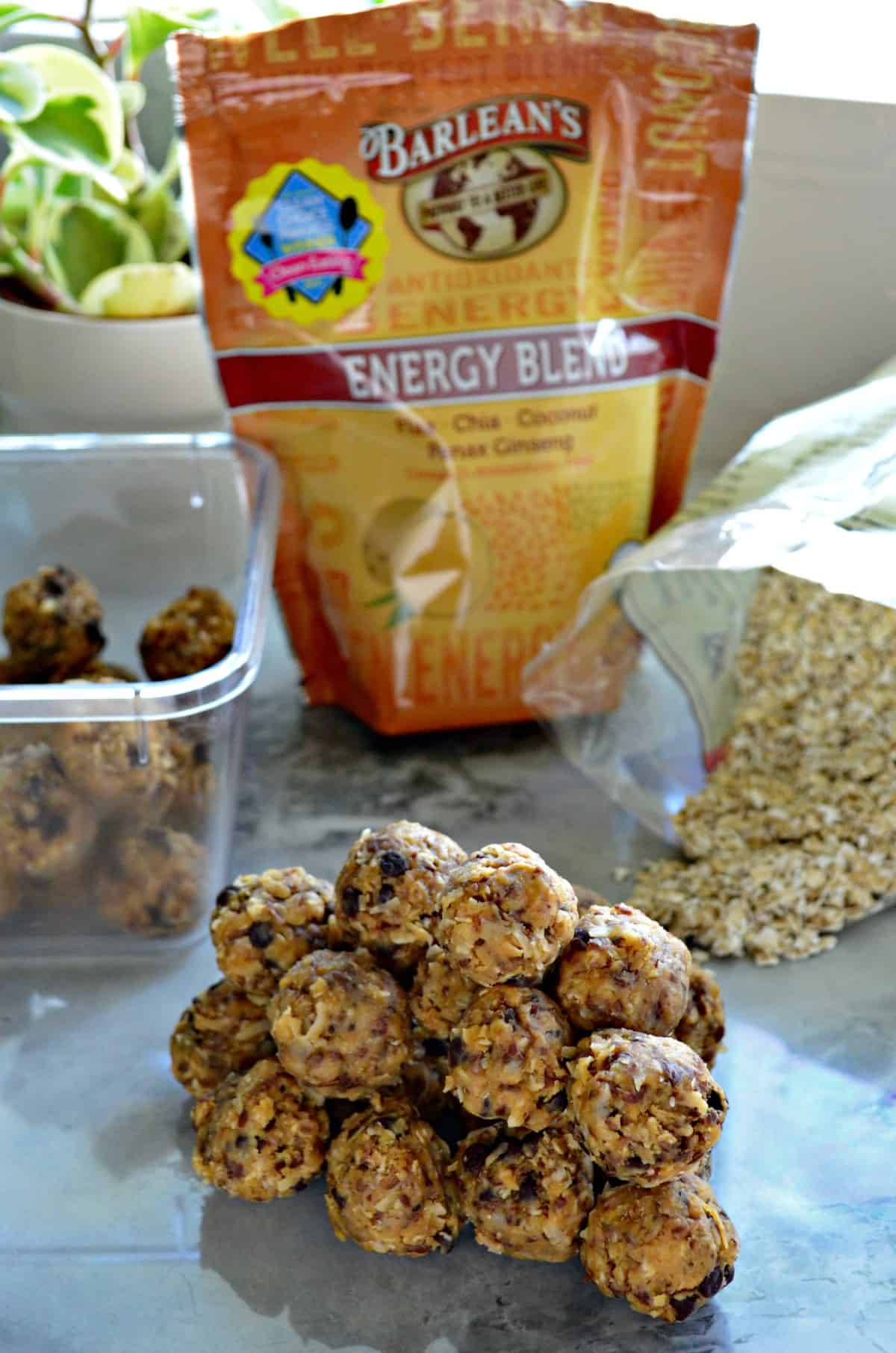 Peanut Butter Chocolate Chip Protein Balls stacked on countertop in front of ingredients and tupperware.