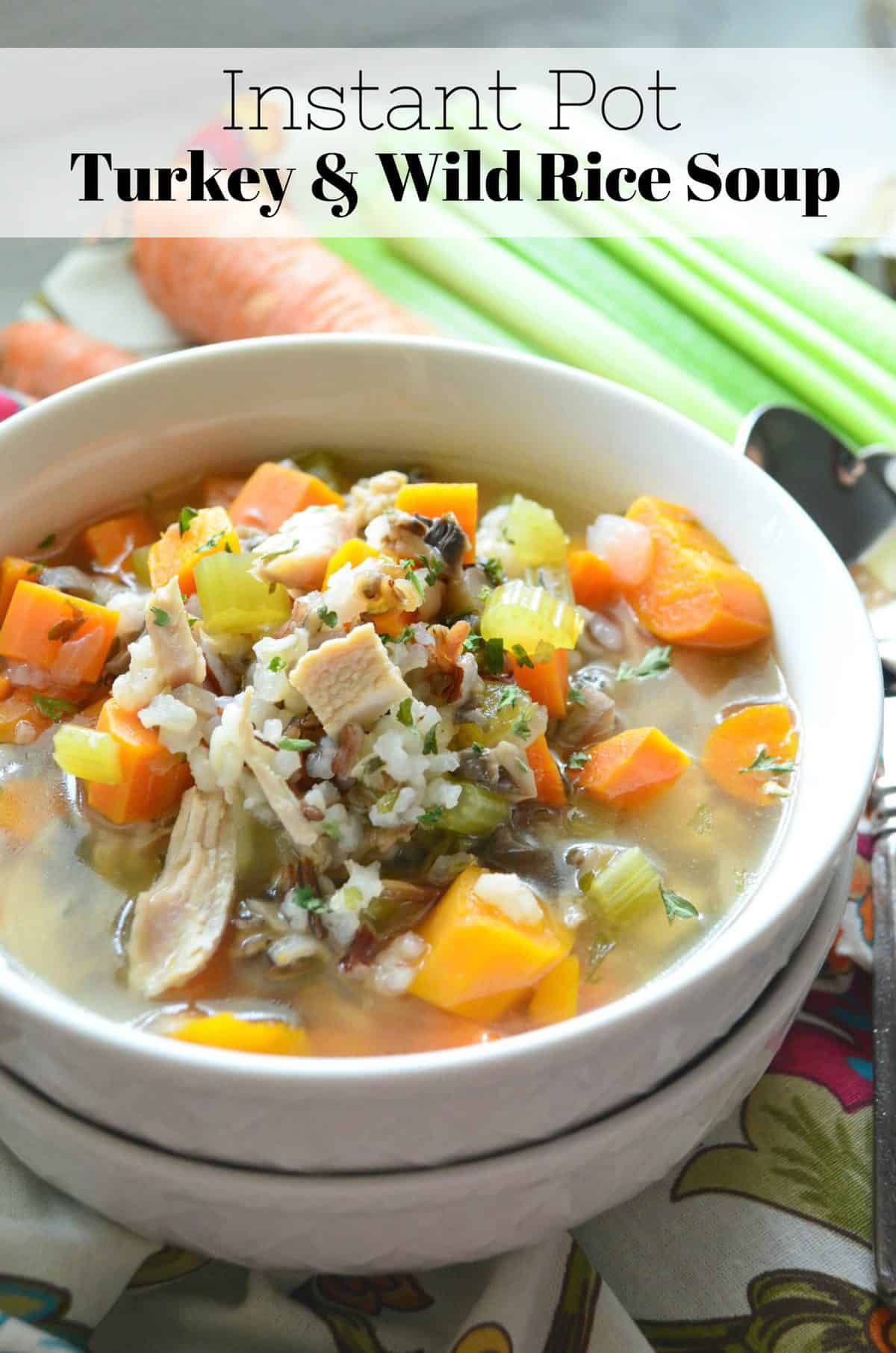Instant Pot Turkey & Wild Rice Soup in a white bowl with celery, carrots, rice, herbs, and turkey visible.