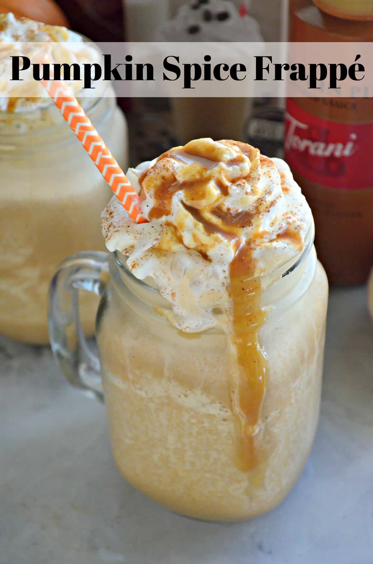 mason jar glass mug with handle filled with light orange frozen drink topped with whipped cream and caramel.