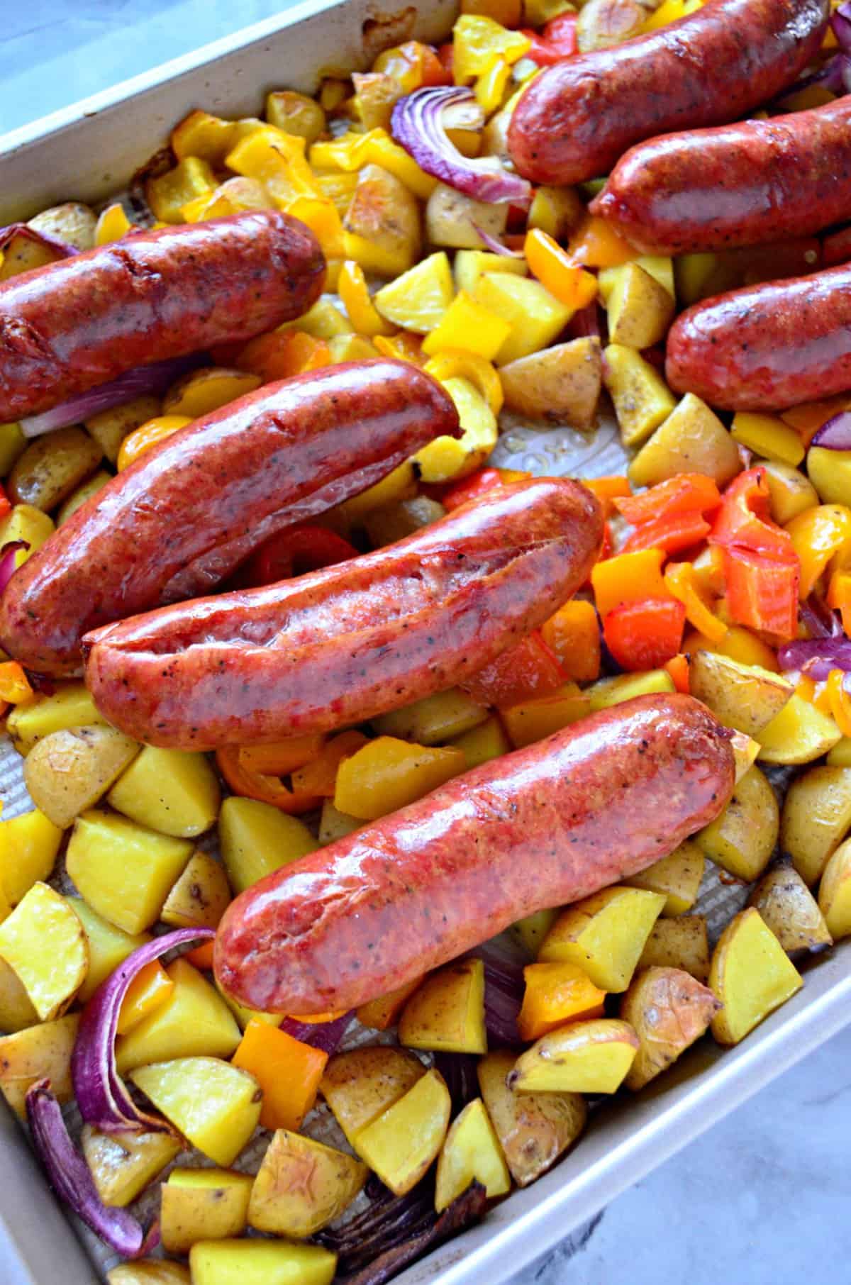 closeup browned Kielbasa sausage, diced Potato, and Peppers on sheet pan.