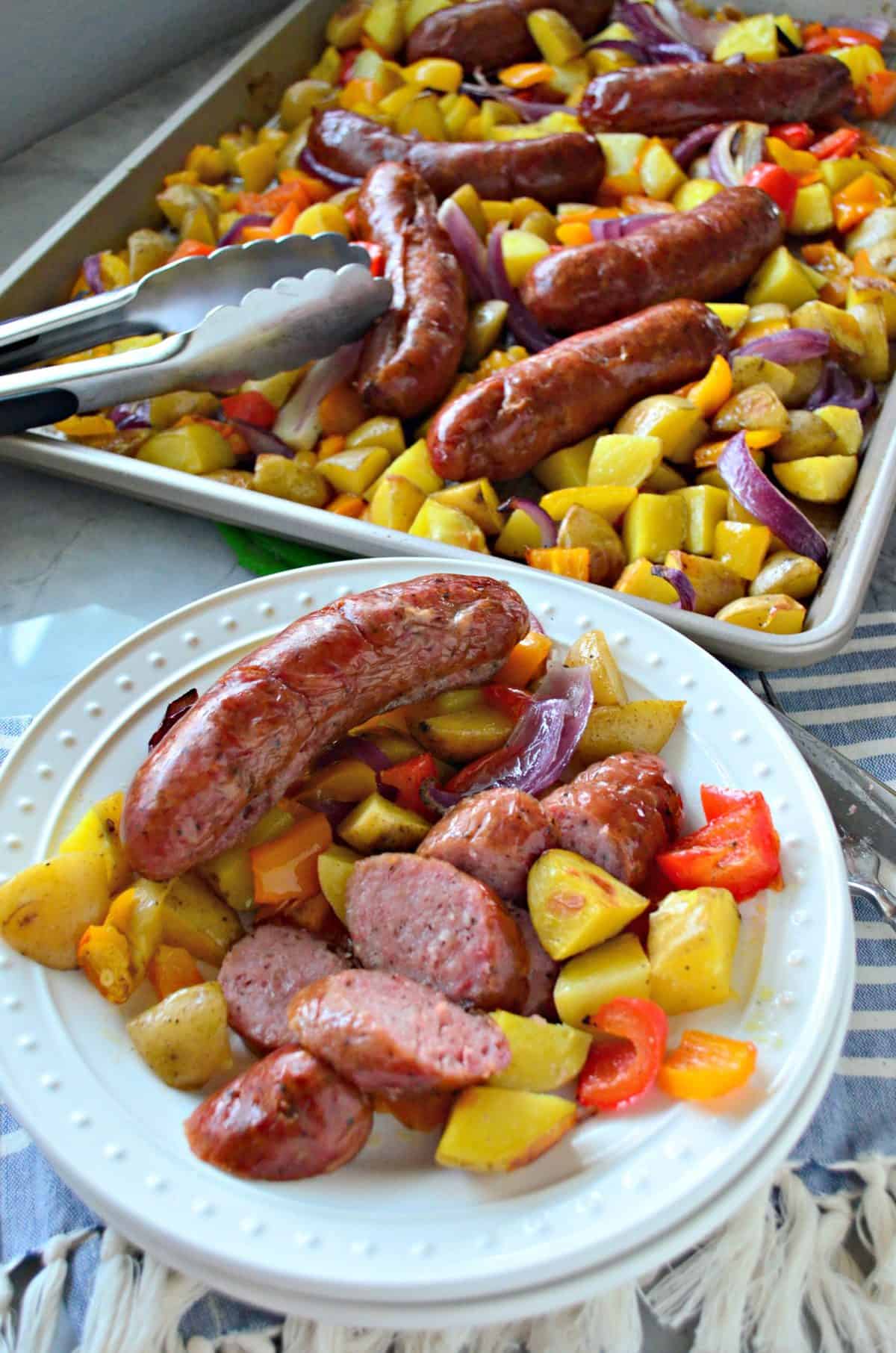 plated sliced browned Kielbasa sausage, diced Potato, and Peppers in front of sheet pan with leftovers.