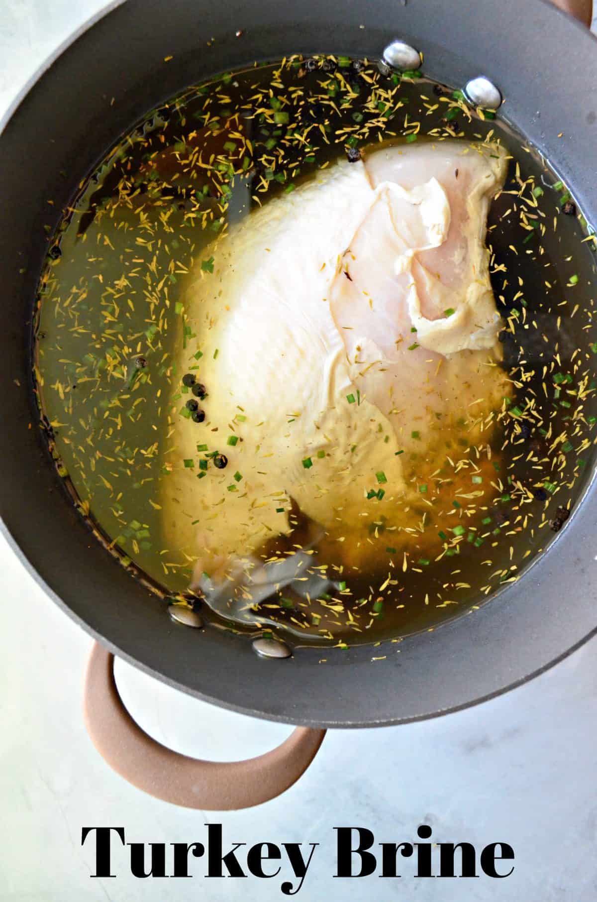 top view of raw Turkey brining in yellowish liquid with herbs in pot with title text.