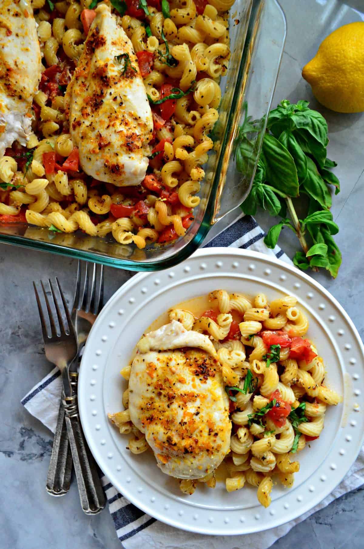 plated chicken breast and cavatapi with herbs and tomatoes next to baking dish of leftovers.