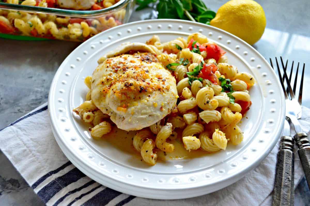 plated chicken breasts and cavatapi with herbs and tomatoes next to forks in front of lemon.