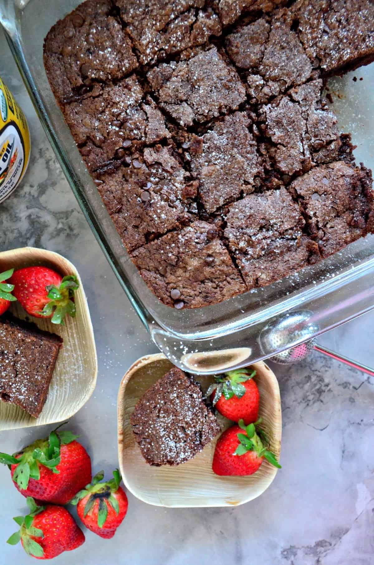 top view of brownies with powdered sugar cut into squares in glass baking dish.