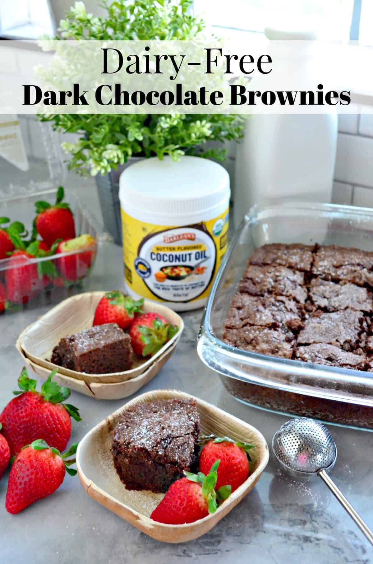 2 square bowls with slice of chocolate brownie and fresh strawberries in front of brownie pan.