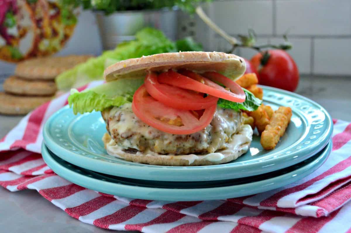 Turkey and Chickpea Burger with Dill Havarti, tomato slices, lettuce, and white sauce plated with fries.