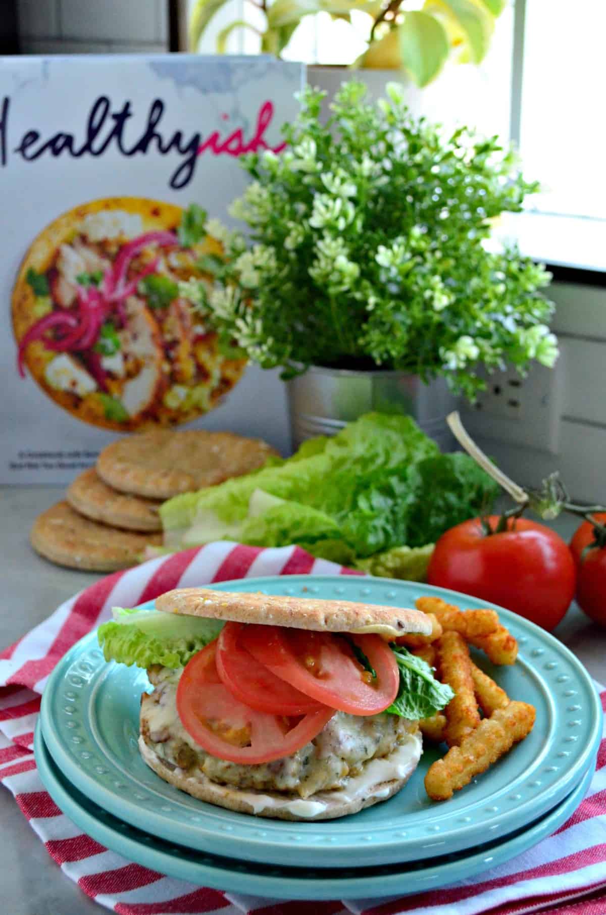 Turkey and Chickpea Burger with Dill Havarti, tomato slices, lettuce, and white sauce plated with fries.