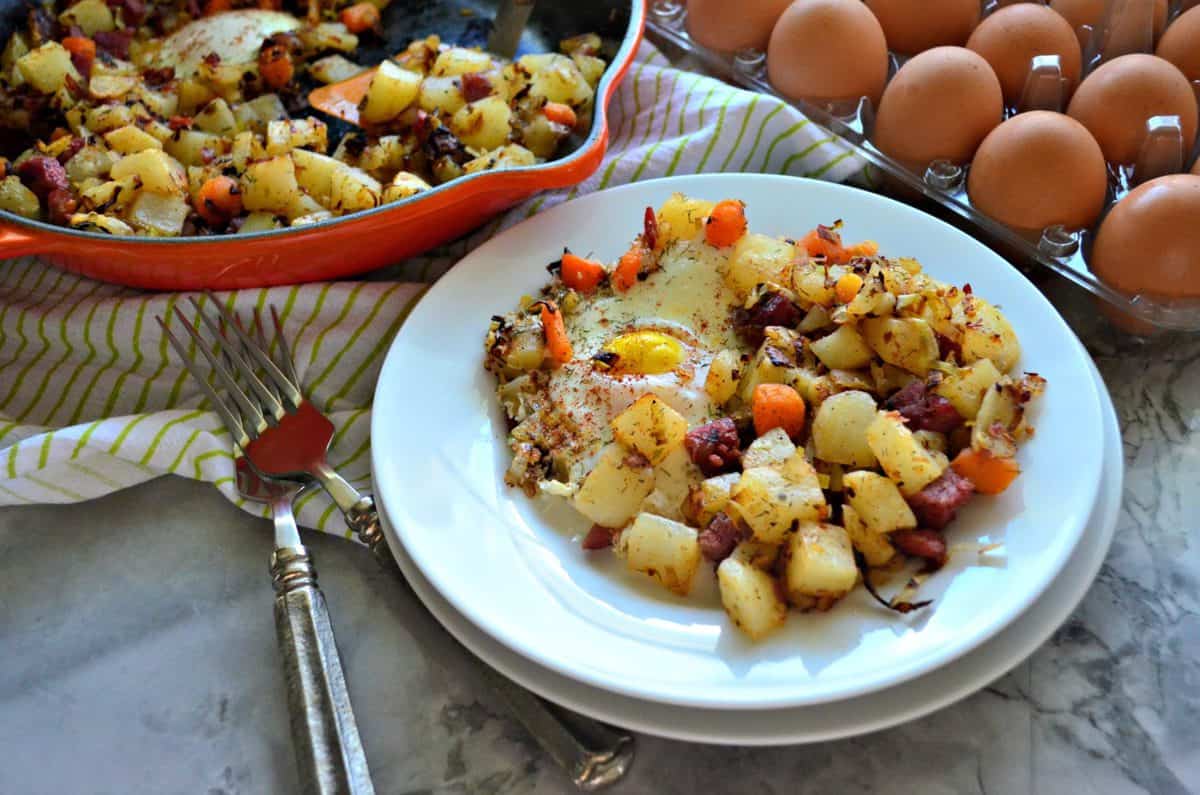 plated Corned Beef Hash with over easy eggs in front of egg carton and skillet.