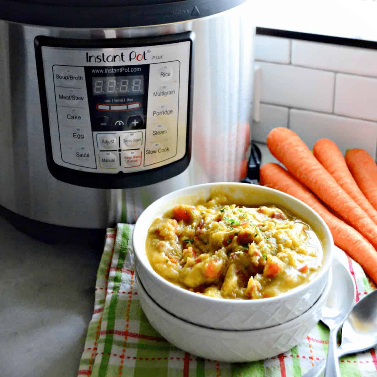 White bowls stacked with soup with an Instant Pot and carrots in background.