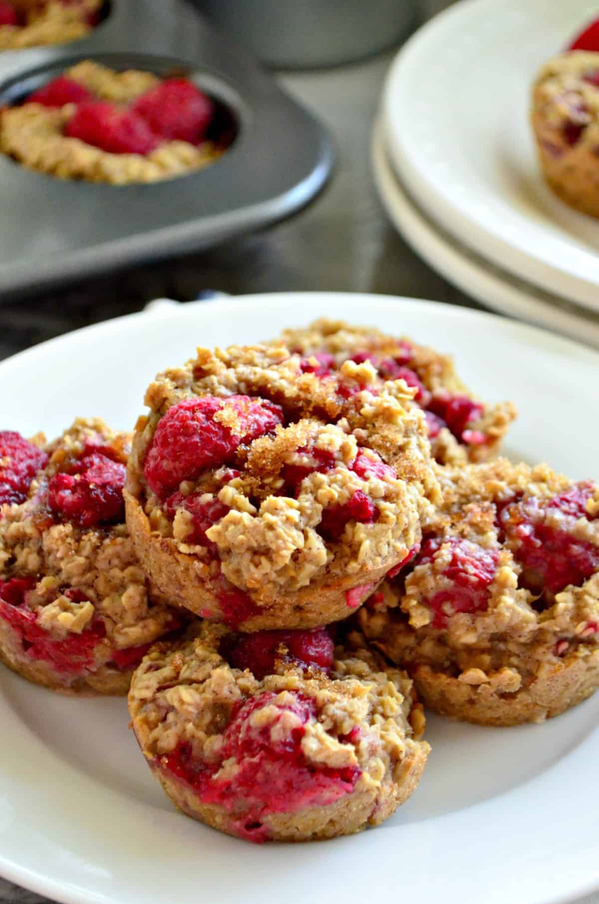 closeup of 5 stacked Banana Raspberry Oatmeal Muffins on white plate.