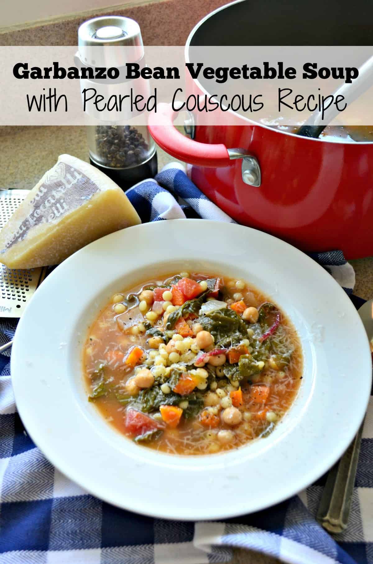 Garbanzo Bean Vegetable Soup with Pearled Couscous in a bowl next to red pot, pepper, and cheese.